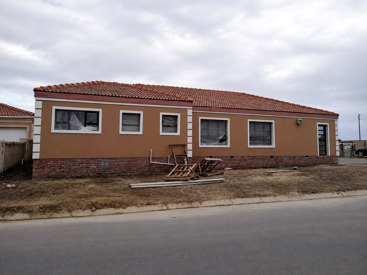 Completed single-story house with red tiled roof and landscaped yard
