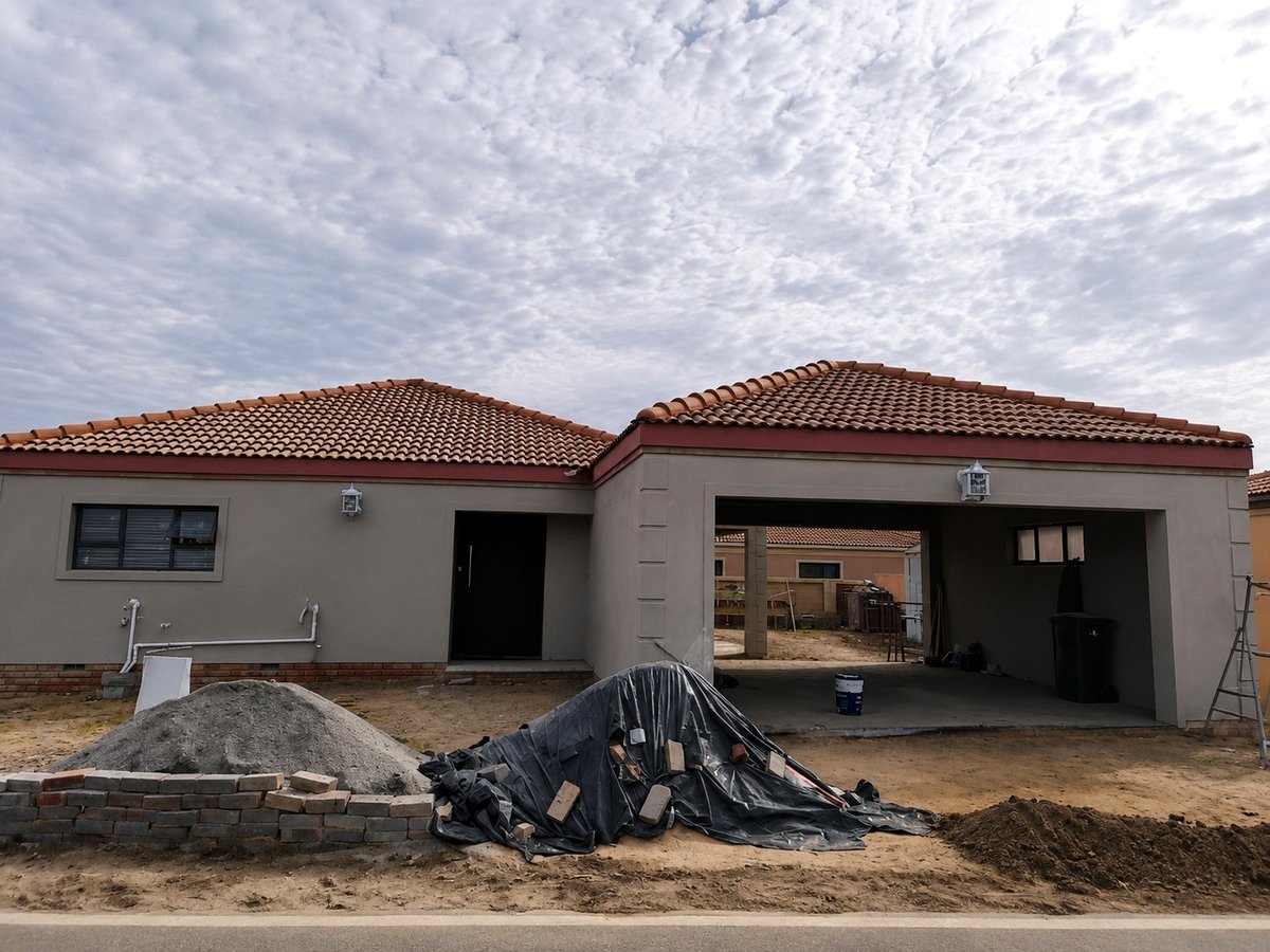 House with garage under construction with building materials on site