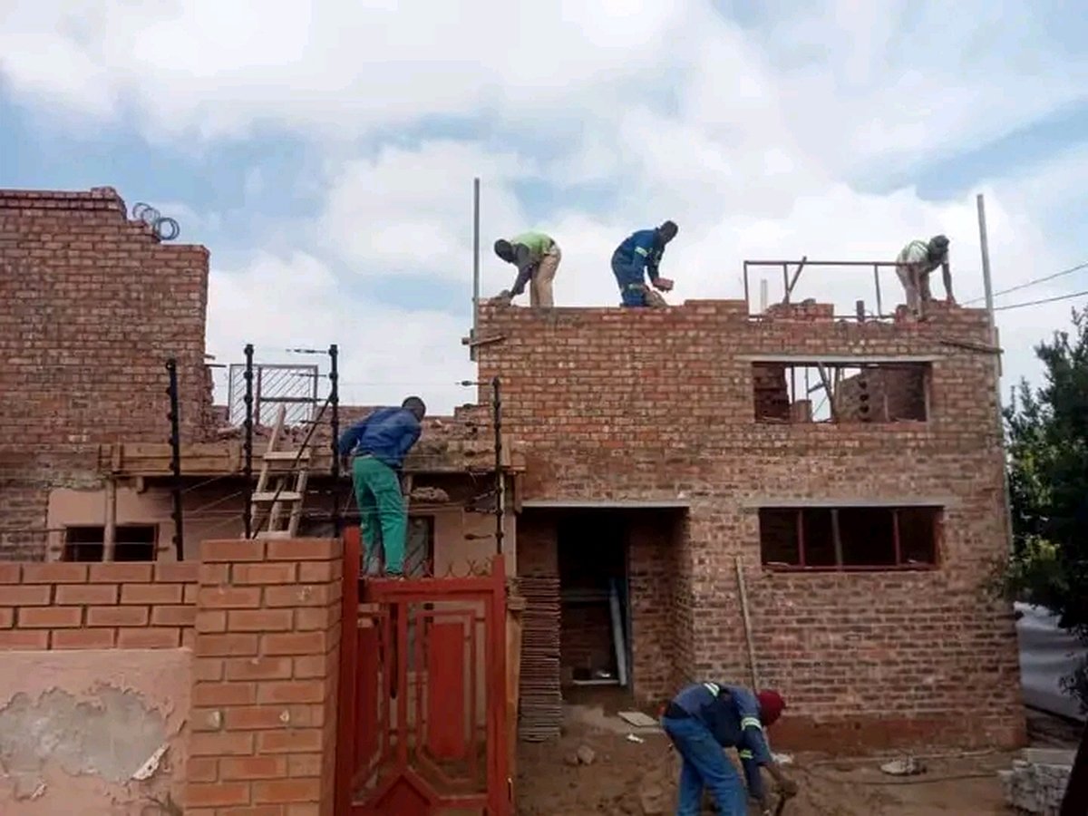 Bricklayers building walls on two-story house construction site