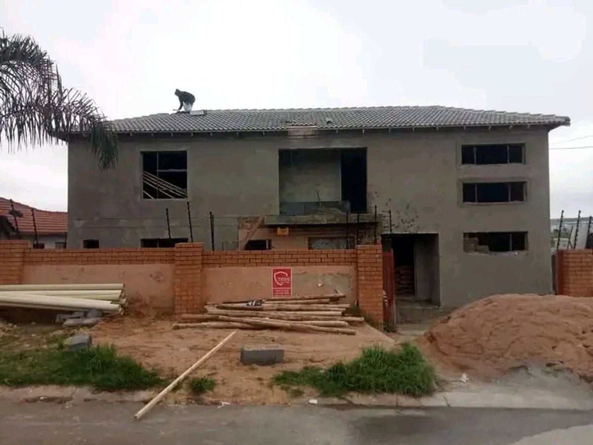 Gray house with worker on roof during final construction phase